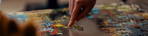 Colorful jigsaw puzzle pieces being assembled on a table, wide banner