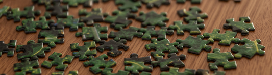 Scattered jigsaw puzzle pieces on a wooden table, wide banner